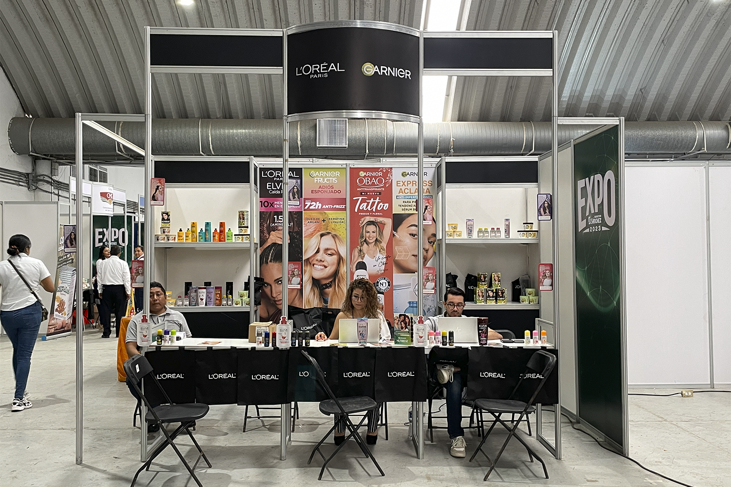 Expo Sánchez 2023: stand de esquina con branding vertical y mesas de atención