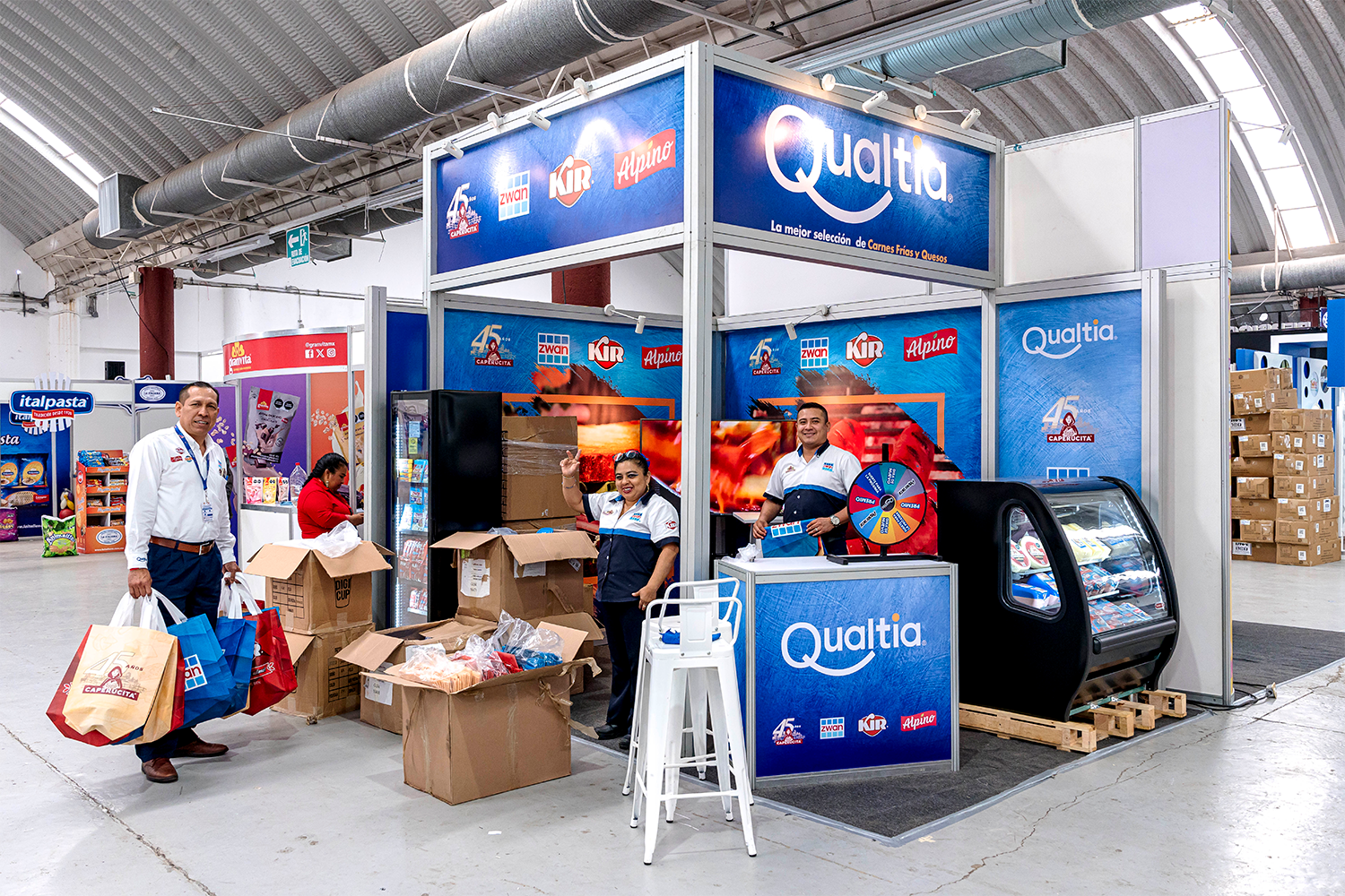 Stand de sistema para la marca Qualtia con refrigerador y rueda de la fortuna.