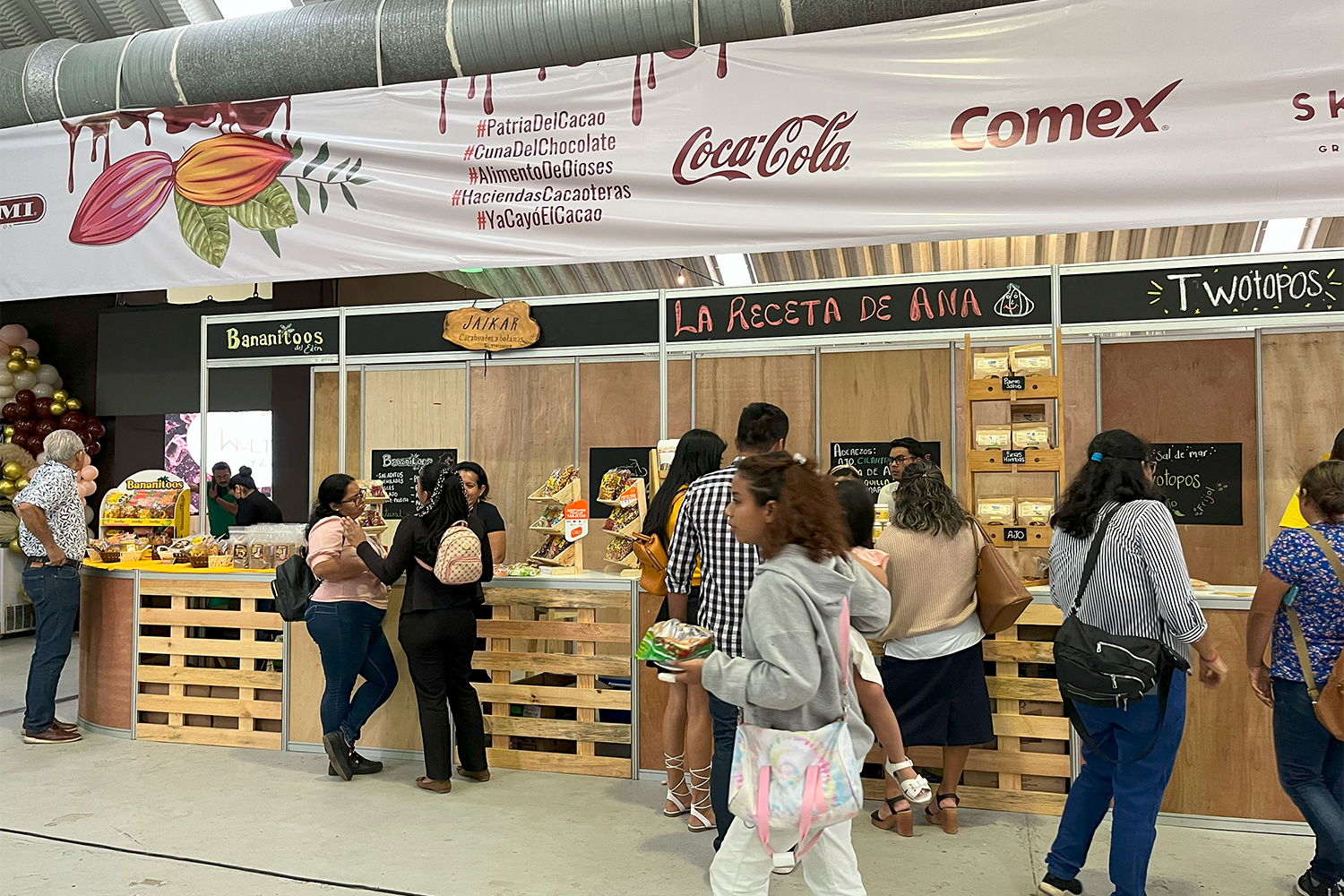 Stands de expositores con estilo rústico de madera en el área comercial del festival.
