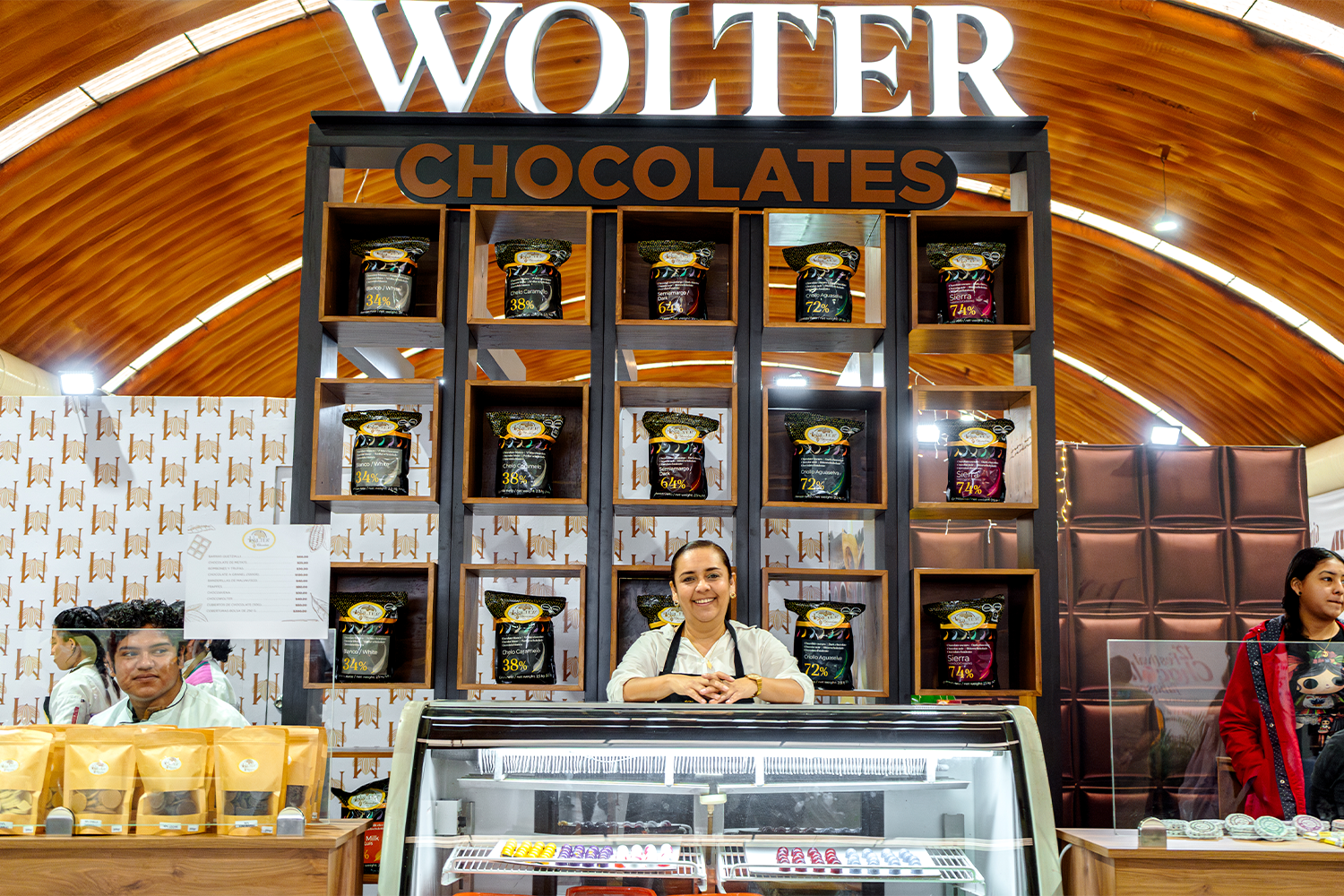 Expositora sonriendo en el stand de diseño premium de Wolter Chocolates.