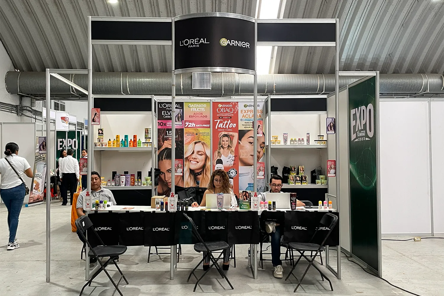 Expo Sánchez 2023: stand de esquina con branding vertical y mesas de atención