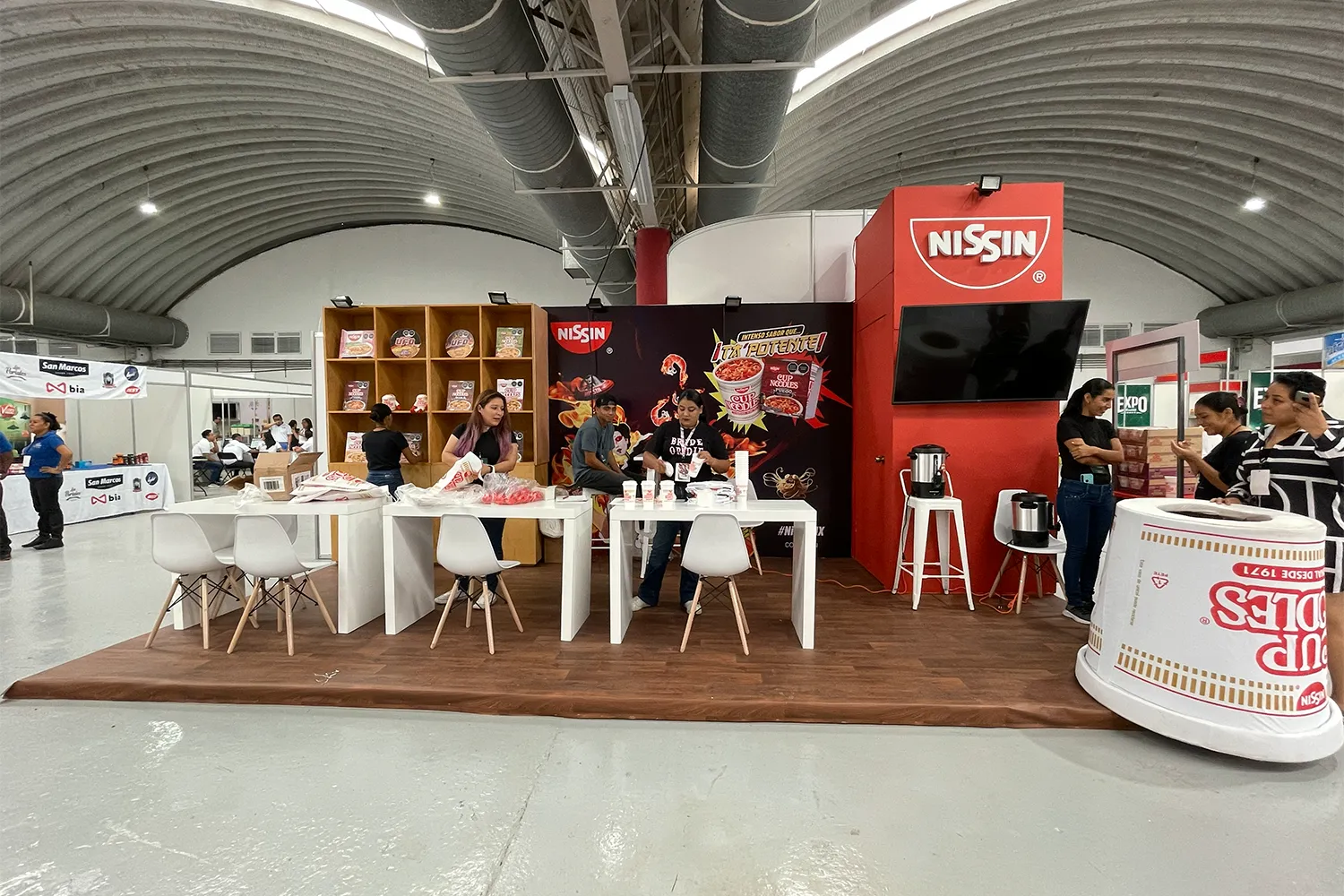 Expo Sánchez 2023: stand central con barra curva y mobiliario blanco